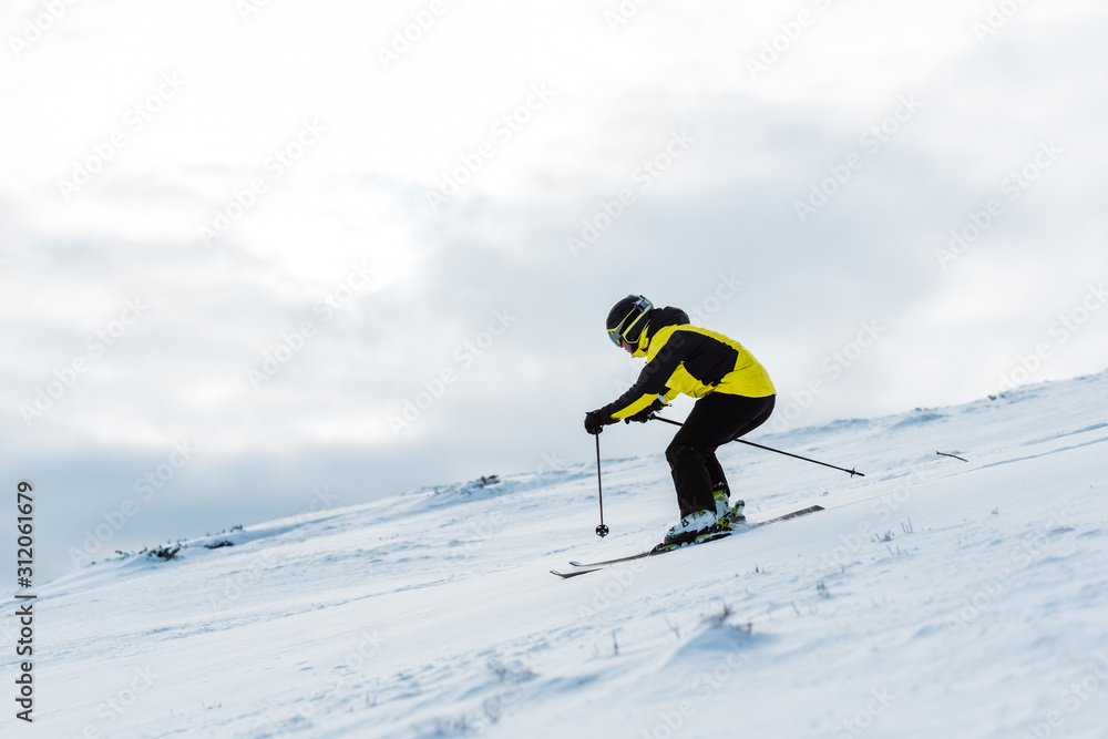 sportsman in helmet and goggles skiing on slope in wintertime