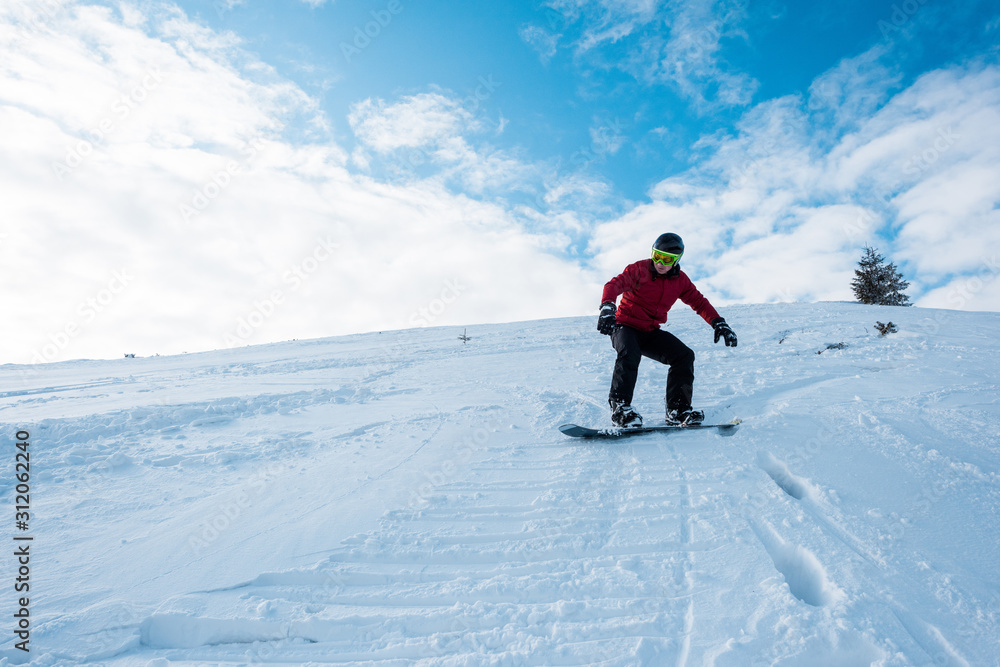 athletic snowboarder riding on slope in winter