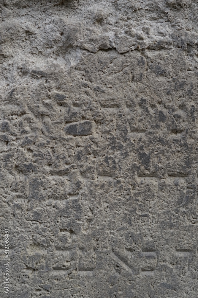 Ausschnitt eines verwitterten jüdischen Grabstein mit hebräischer Inschrift
