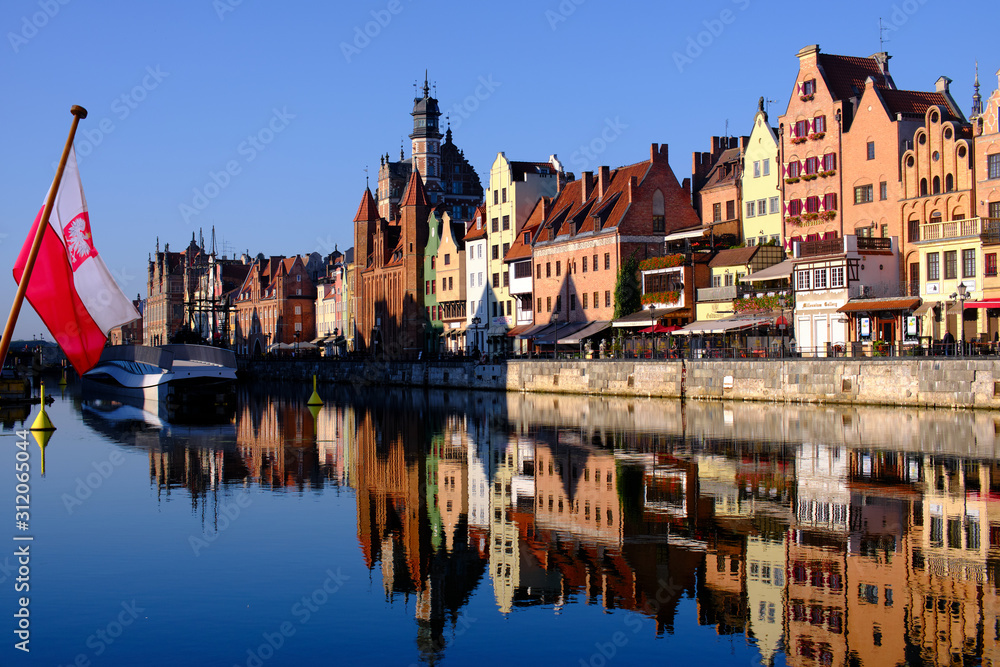 Obraz premium Colorful hanseatic city facades of historic houses close to the Motława river in Gdansk, a port city on the Baltic coast of Poland, in the foreground a polish flag