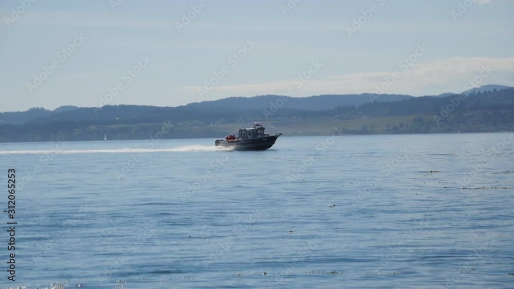 speed boat races along calm waters with mountains in distance speed boat races along calm waters with mountains in distance