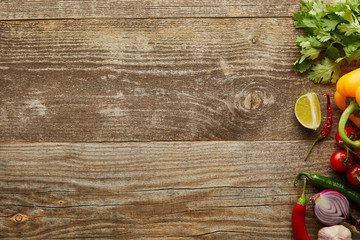 Top view of raw vegetables with lime slice and greenery on wooden background with copy space