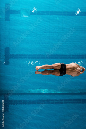 top view of muscular swimmer diving into water