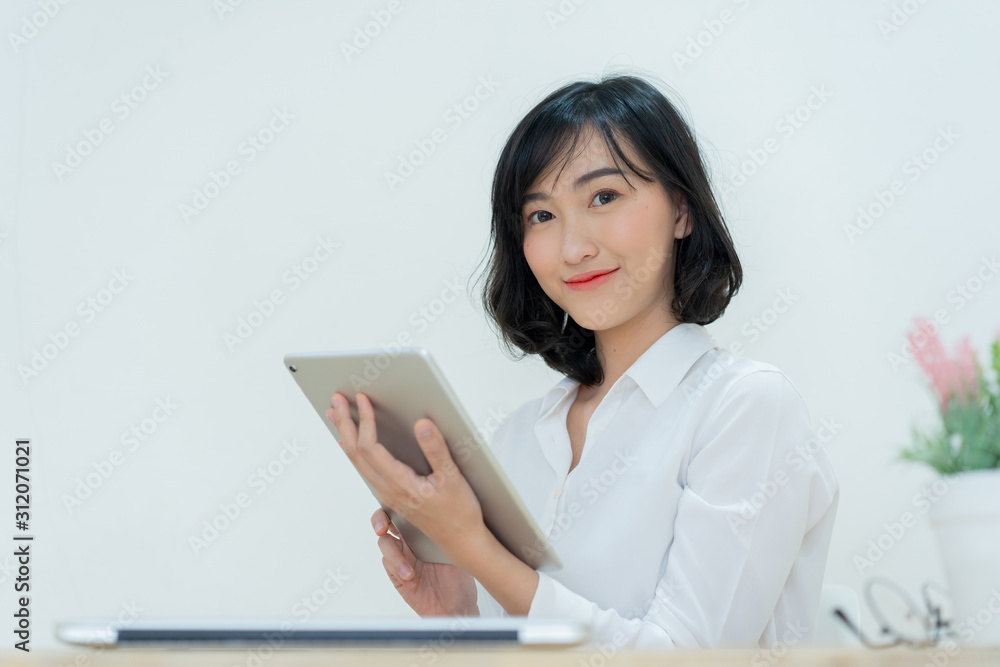 close up young japanese employee woman holding tablet to responses e-mail with customer or vendor and check to do list at desk in office room for work from home and social distance concept close up young japanese employee woman holding tablet to responses e-mail with customer or vendor and check to do list at desk in office room for work from home and social distance concept