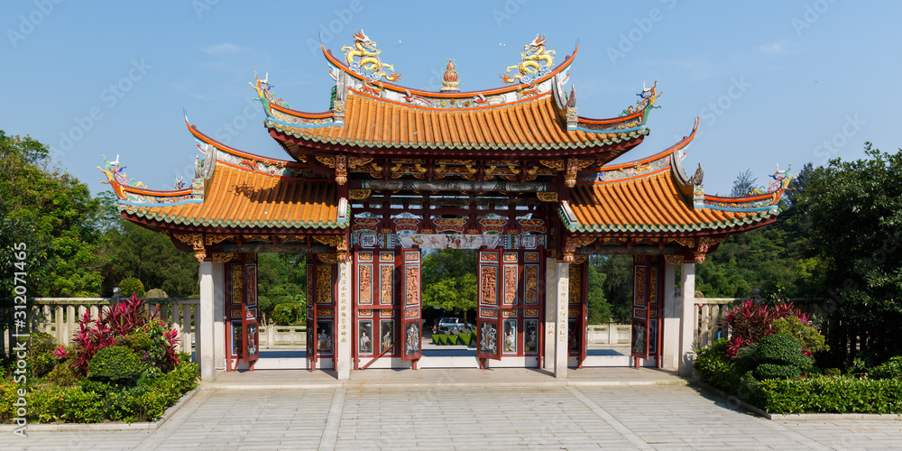 MACAO, CHINA - May 29, 2017: View on entrance gate to A-Ma Cultural Village. Featuring three decorated doors, two golden colored dragons and an orange colored, curved roof (typical for asian temples). MACAO, CHINA - May 29, 2017: View on entrance gate to A-Ma Cultural Village. Featuring three decorated doors, two golden colored dragons and an orange colored, curved roof (typical for asian temples).