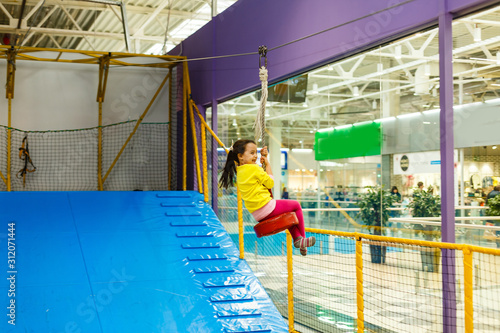 Adorable Little girl laughing happily, riding upside down on a bungee swing on the playground in yellow. Happiness, freedom, enjoyment, health.