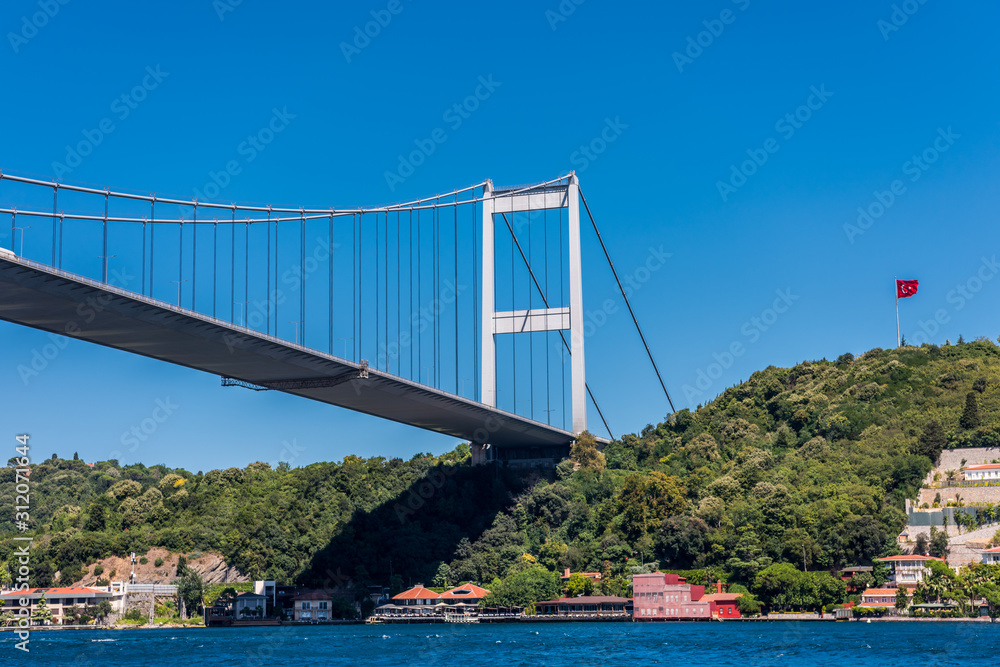 Beautiful view of Bosphorus bridge cross the Bosphorus strait with Turkish National flag, Istanbul, Turkey, view on a cruise ship sailing on the Bosphorus strait Beautiful view of Bosphorus bridge cross the Bosphorus strait with Turkish National flag, Istanbul, Turkey, view on a cruise ship sailing on the Bosphorus strait