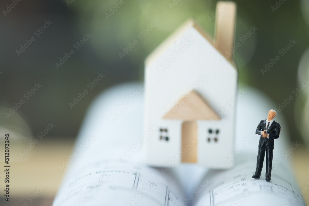 Miniature businessman stand on building plan and home. Miniature businessman stand on building plan and home.