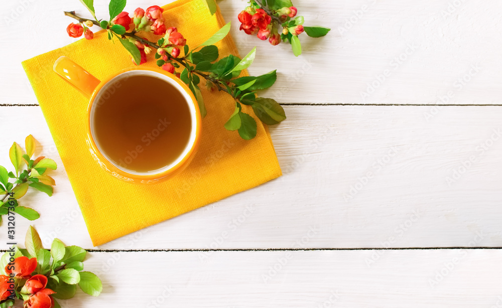 a cup of green tea on a yellow napkin with branches of yellow flowers top view. a cup of green tea on a yellow napkin with branches of yellow flowers top view.