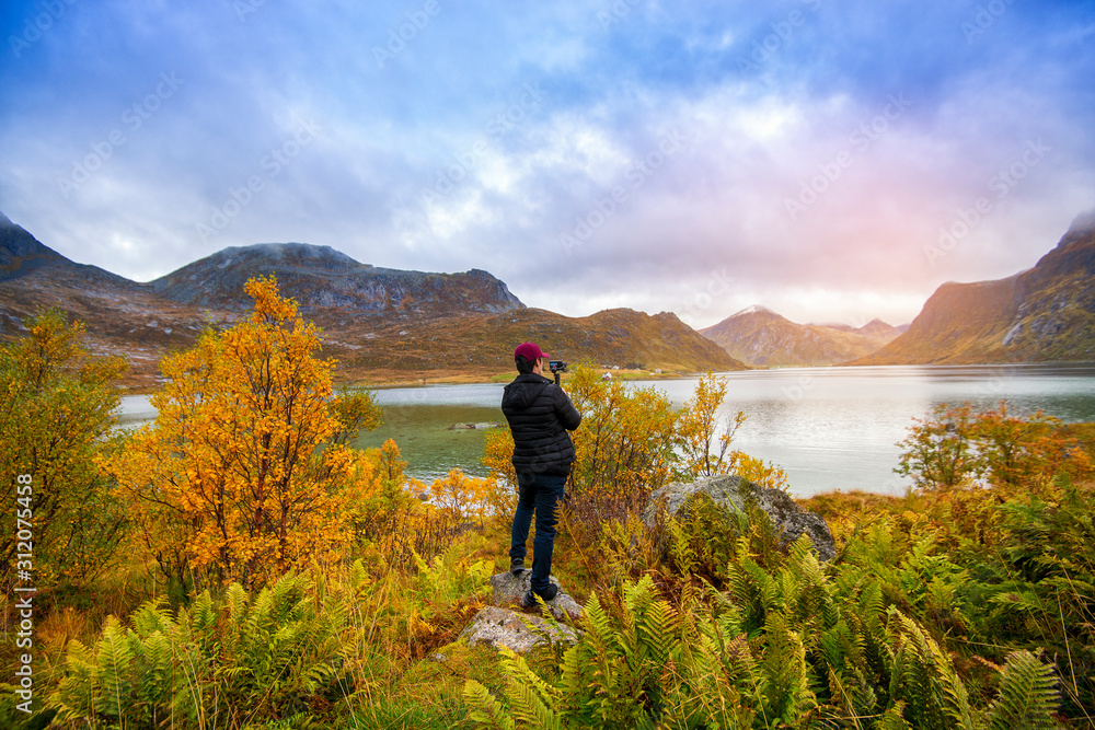 A man is photographing  beautiful view in Lofoten , Norway