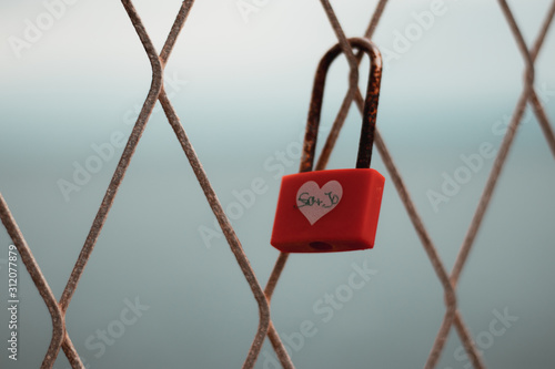 Colored rusted love padlocks with initials on a fence in split croatia , dramatic cold day. Concepts of love drama