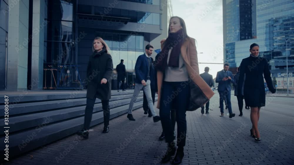 Office Managers and Business People Commute to Work in the Morning or from Office on a Cloudy Day on Foot. Pedestrians are Smart Casually Dressed. Successful People Holding Smartphones. Office Managers and Business People Commute to Work in the Morning or from Office on a Cloudy Day on Foot. Pedestrians are Smart Casually Dressed. Successful People Holding Smartphones.