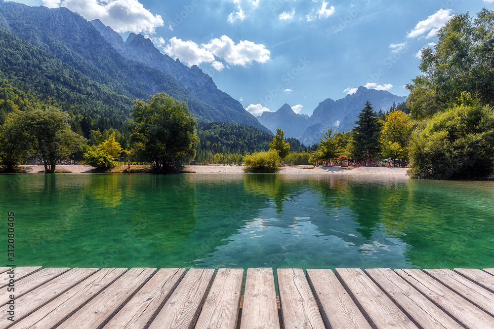 Awesome alpine highlands in summer. Lake with Wooden Pier and mountain peaks on background, in sunny day. Beautyful Nature Scene. Jasna lake in Julian Alps, Kranjska gora, Slovenia.