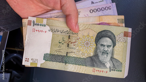 Hand holding Iranian Rial. photo