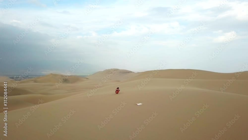 Aerial, orbit, drone shot, around a girl taking pictures, on sand dunes, at the Atacama desert, on a sunny day, in south Peru Aerial, orbit, drone shot, around a girl taking pictures, on sand dunes, at the Atacama desert, on a sunny day, in south Peru