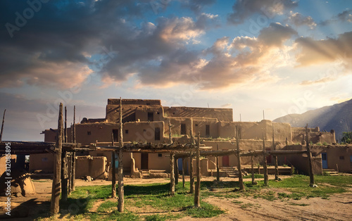 Taos Pueblo Illuminated by the Morning Sun over the Sangre de Cristo Mountains in New Mexico photo