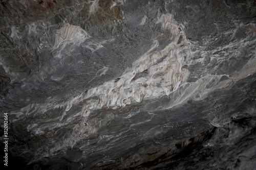 Gray karst cave. Rock formations in the cave, stalactites and stalagmites. Abstract gray grunge background. Stone texture background. Spotted abstract stone. Russia, Bashkortostan, a fairy cave