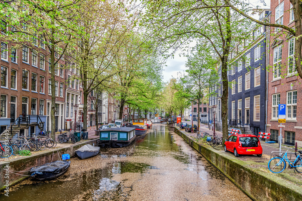 Beautiful view of Amsterdam canal, boats and medieval typical Dutch houses in a spring day. Amsterdam, Netherlands.
