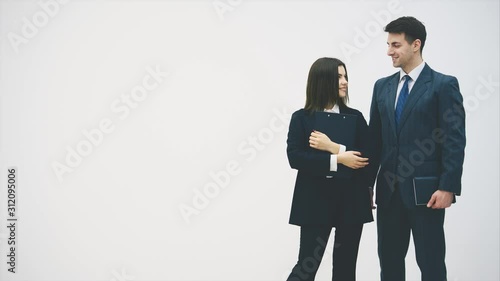 Business couple standing, looking at one anoter, nodding, holding clipboard and notebook. photo