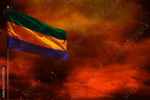 Fluttering Gabon flag mockup with blank space for your text on crimson red sky with smoke pillars background. Troubles concept.