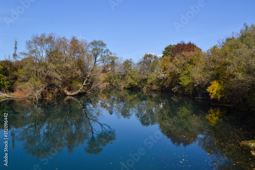 Fall colors reflectio in blue river. Vivid nature