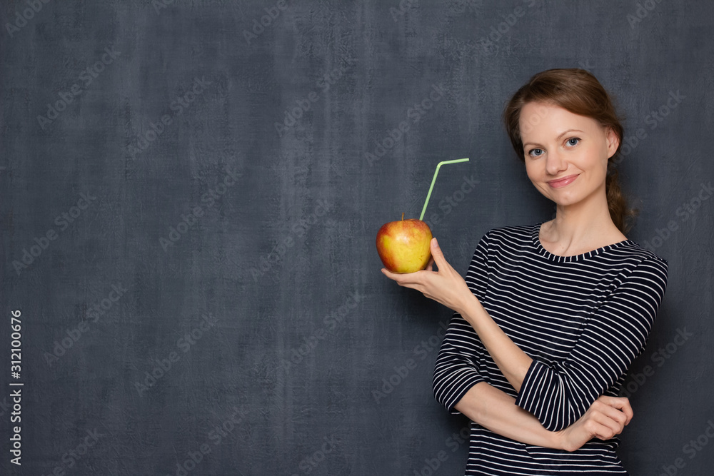 Portrait of happy young woman holding ripe apple with drinking straw Portrait of happy young woman holding ripe apple with drinking straw