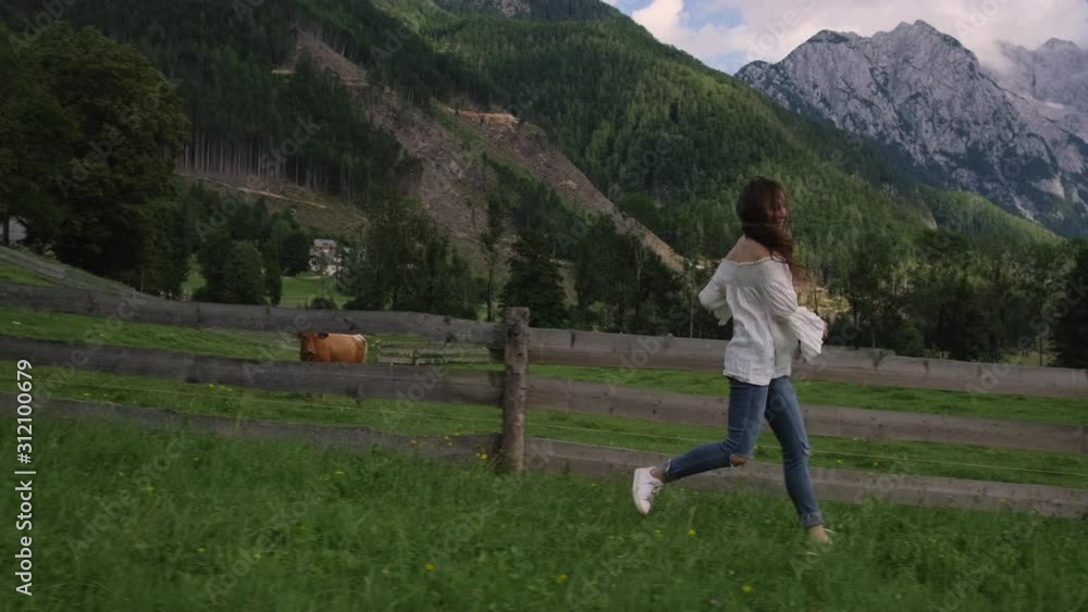 country girl is running in farm in Alpine meadows with cows pasture country girl is running in farm in Alpine meadows with cows pasture