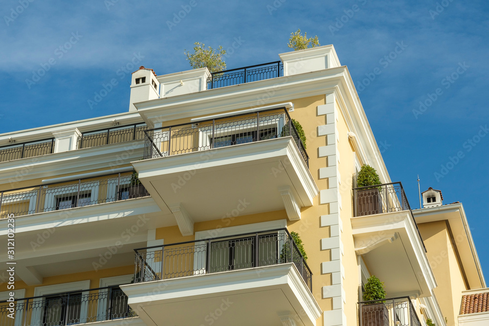 Obraz premium Tivat, Montenegro, December 16, 2019: Facade of the building of the Regent hotel on the Tivat embankment. The walls of the building are light yellow in the background of a blue sky