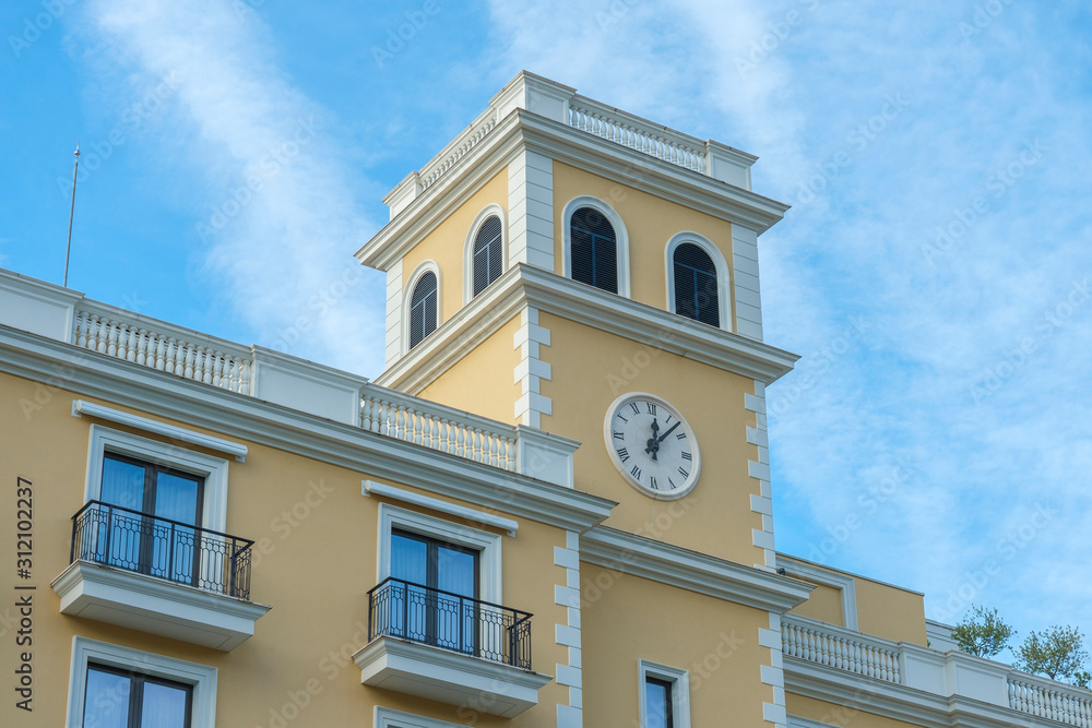 Tivat, Montenegro, December 16, 2019: Facade of the building of the Regent hotel on the Tivat embankment. The walls of the building are light yellow in the background of a blue sky