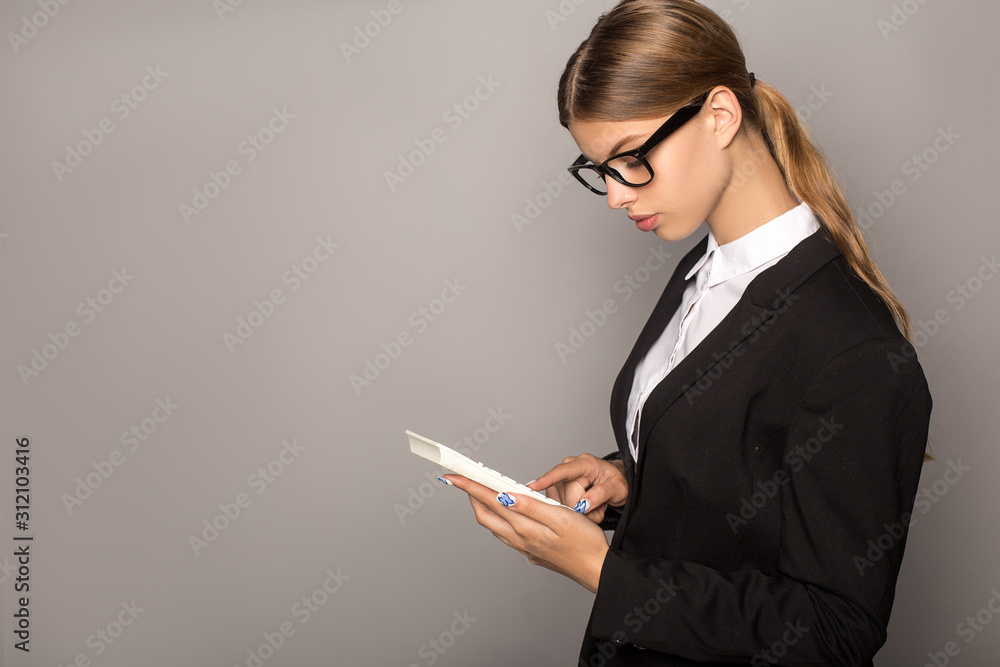 businesswoman in glasses using calculator isolated on grey businesswoman in glasses using calculator isolated on grey