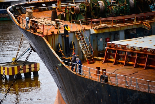 Konstfotografi Two seafarers working on the main deck of old rusty bulk carrier