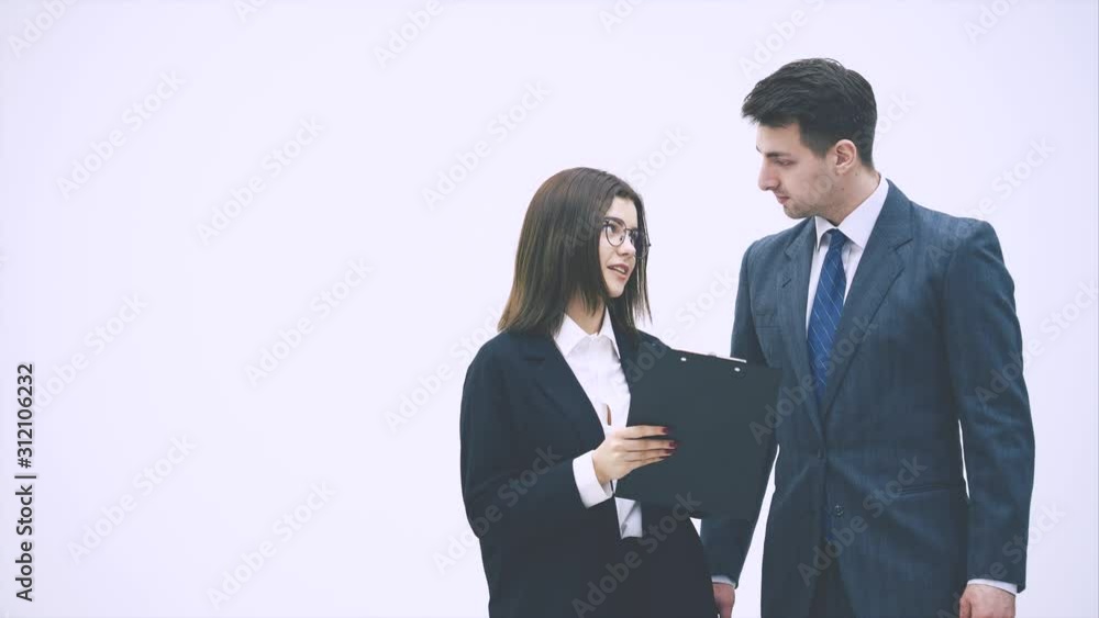 Pretty businesswoman standing with tablet in her hands, explaining something to her partner. Businessman on her side is listening, nodding. Pretty businesswoman standing with tablet in her hands, explaining something to her partner. Businessman on her side is listening, nodding.
