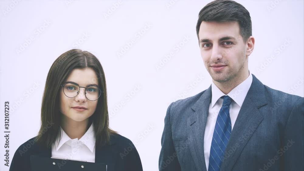 Nice business couple standing, looking at one another, then at the camera, smiling. Nice business couple standing, looking at one another, then at the camera, smiling.
