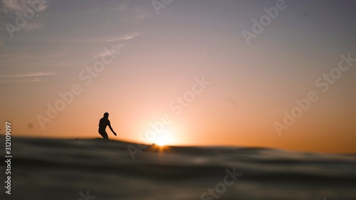 silhouette of woman surfing at sunset