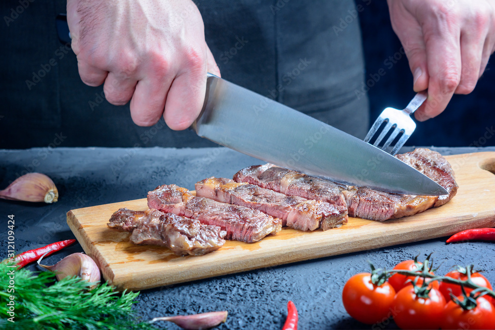 Chef cuts beef steak. Tasty meat of medium roast.