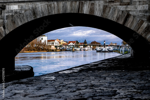 Blick auf ein altes Schiff entlang der Donau, durch die steinerne Brücke