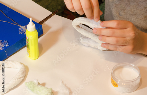 Materials for making figures from paper and cotton wool. Design, creative manufacturing process using glue and paints. Hands sculpting figures out of paper and PVA glue. Selective focus.