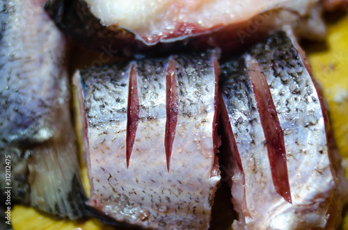 Pieces, chopped raw fish on a wooden board. Fish in macro. Fish in the salt. Worms in the fish. Danger of fish poisoning.