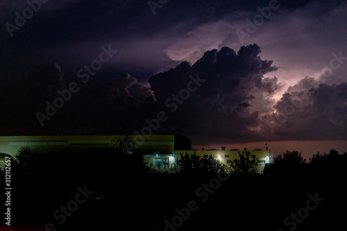Storm clouds with lightning over factory building