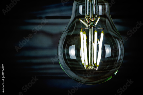 LED light bulb glowing on wooden background closeup.