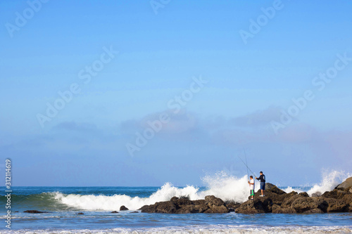 Gone Fishing - Two men fishing on the rocks at the shore.