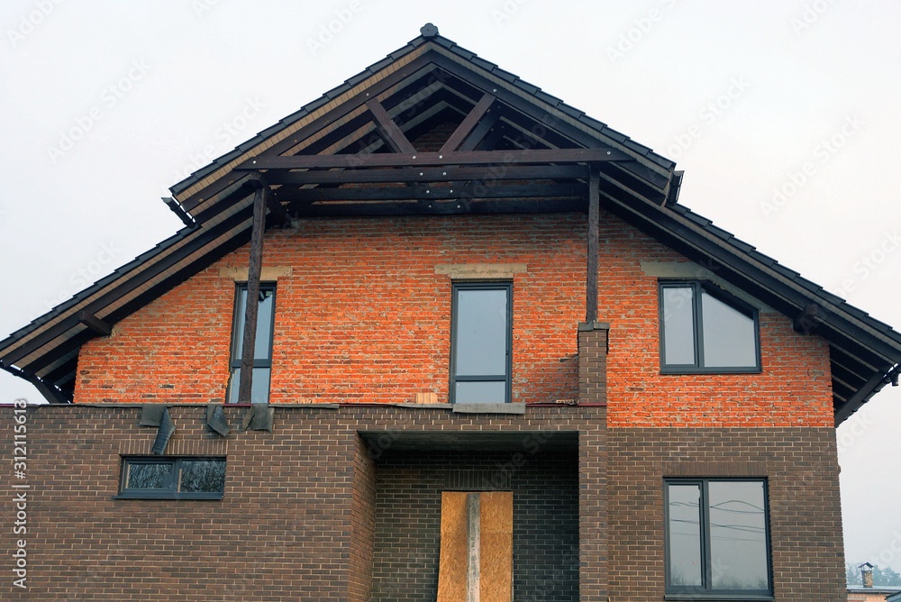 facade of a private house of red and brown bricks in the wall with windows against the sky