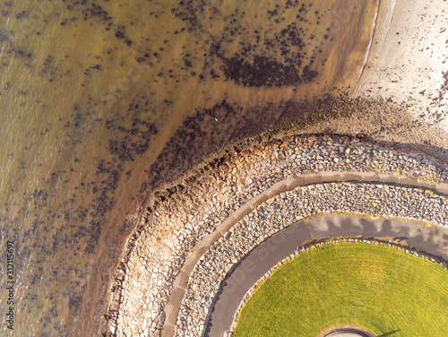 Aerial drone view on a walking path in a park by ocean round shape.