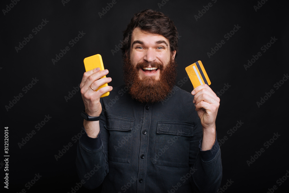 Portrait of amazed young man holding smartphone and credit card Portrait of amazed young man holding smartphone and credit card