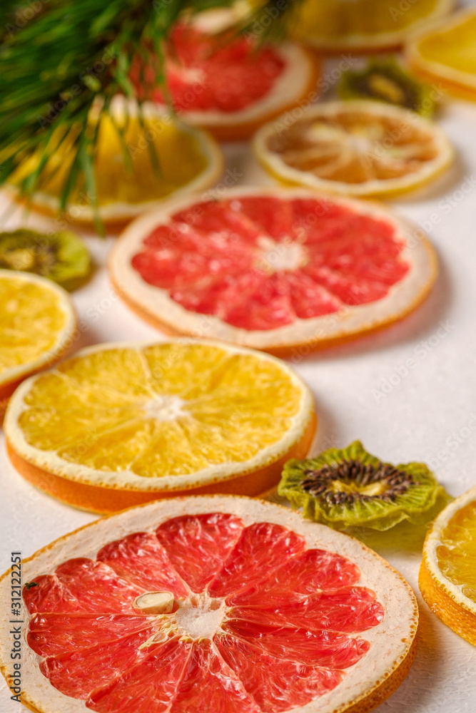 Creative holiday Christmas New Year food fruit texture with dried grapefruit, kiwi, orange and lemon with branch of fir tree, angle view, white background, macro and selective focus Creative holiday Christmas New Year food fruit texture with dried grapefruit, kiwi, orange and lemon with branch of fir tree, angle view, white background, macro and selective focus