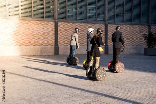 A group of people on eco-friendly Segway scooters on a Spain historic street. Tourists enjoying electric scooters. photo