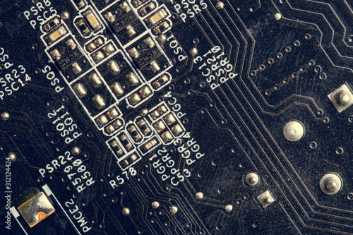 A close up macro photo of a generic technology motherboard circuit board (pcb) light with a blue flash gel on a diagonal angle