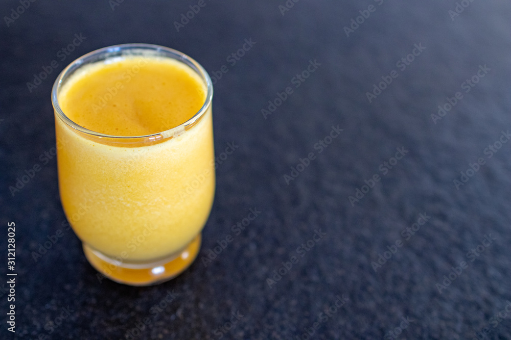 centrifuged glass of organic orange juice. Centrifuge of yellow oranges, fruit juice in a transparent glass on a black granite table. vegan and healthy drinks centrifuged glass of organic orange juice. Centrifuge of yellow oranges, fruit juice in a transparent glass on a black granite table. vegan and healthy drinks