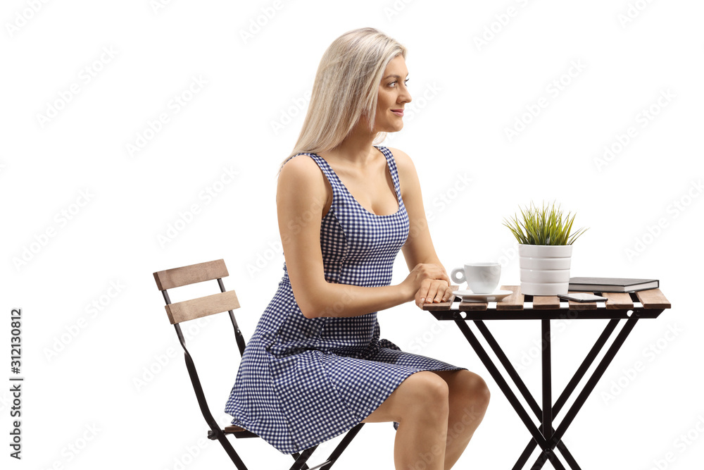 Young blond woman sitting at a coffee table Young blond woman sitting at a coffee table