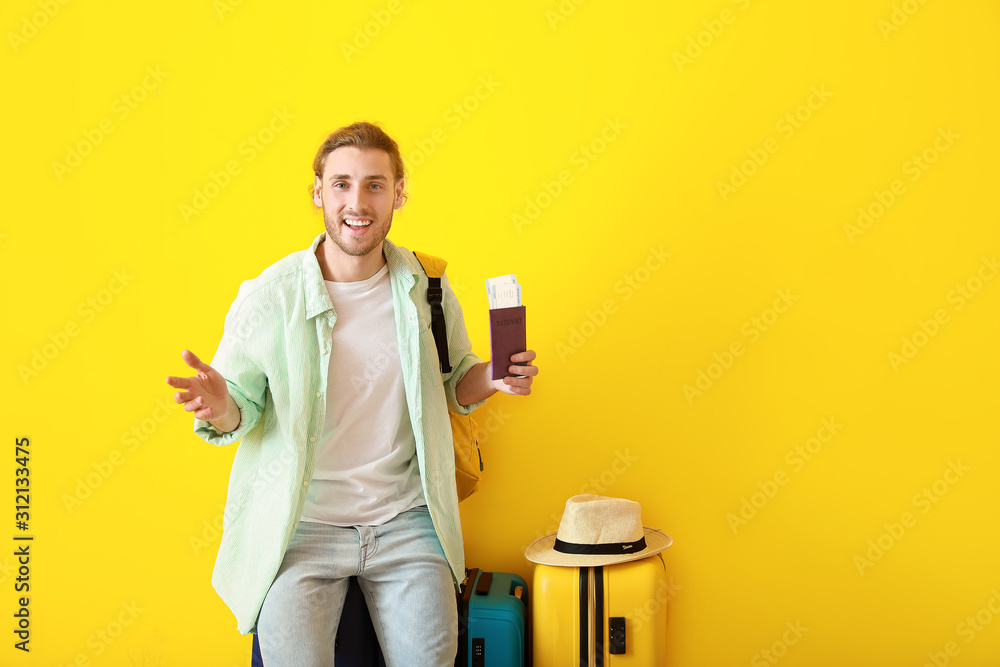 Young male tourist with luggage on color background Young male tourist with luggage on color background